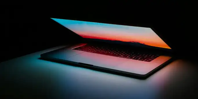 Blog_Technology_partially open laptop in dark space glowing with sunset colors