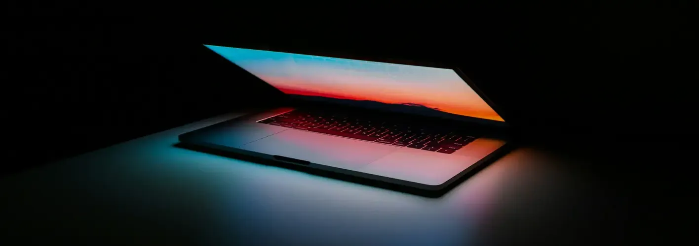 Blog_Technology_partially open laptop in dark space glowing with sunset colors