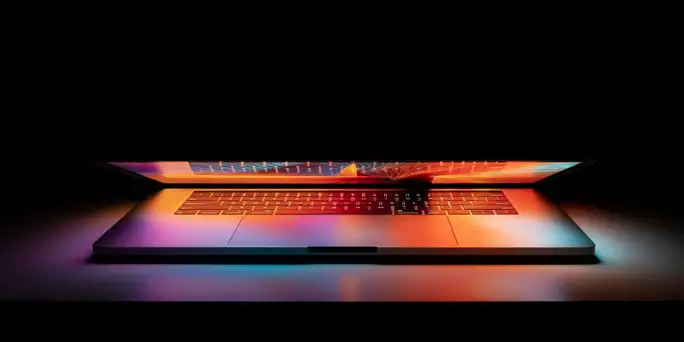 Blog_Technology_partially open laptop in a dark space reflecting a colorful screen on keyboard (Web Optimized)