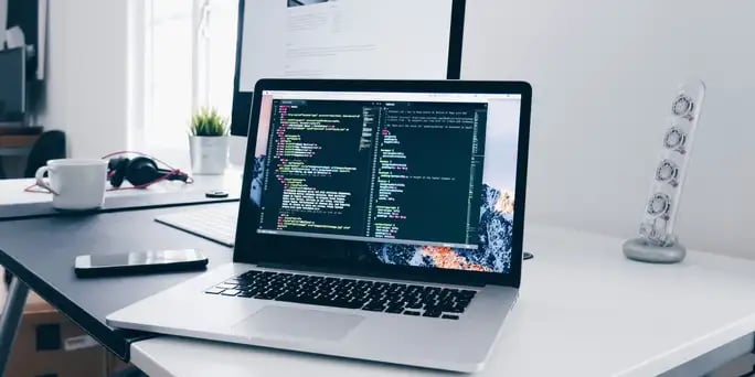 Blog_Technology_laptop with developer code on white desk